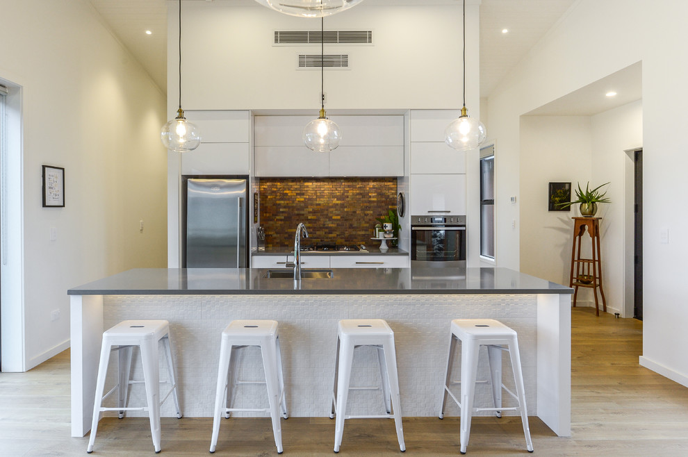 Inspiration for a contemporary galley light wood floor and beige floor open concept kitchen remodel in Hamilton with an undermount sink, flat-panel cabinets, white cabinets, multicolored backsplash, matchstick tile backsplash, stainless steel appliances and an island