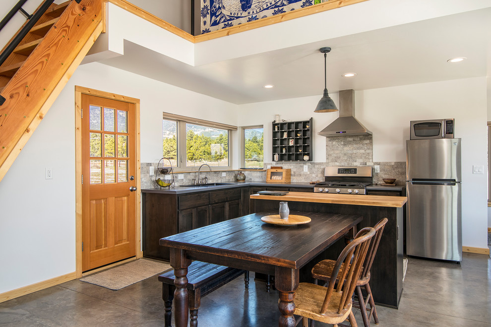 フェニックスにあるラスティックスタイルのおしゃれなキッチン (ダブルシンク、濃色木目調キャビネット、シルバーの調理設備、コンクリートの床、グレーの床、グレーのキッチンカウンター、窓) の写真