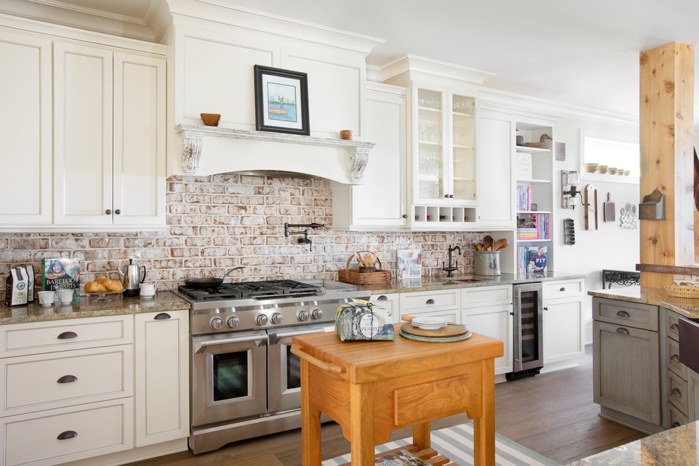 Bild på ett lantligt beige beige kök, med en rustik diskho, skåp i shakerstil, vita skåp, granitbänkskiva, stänkskydd i tegel, rostfria vitvaror, mörkt trägolv, en köksö och brunt golv