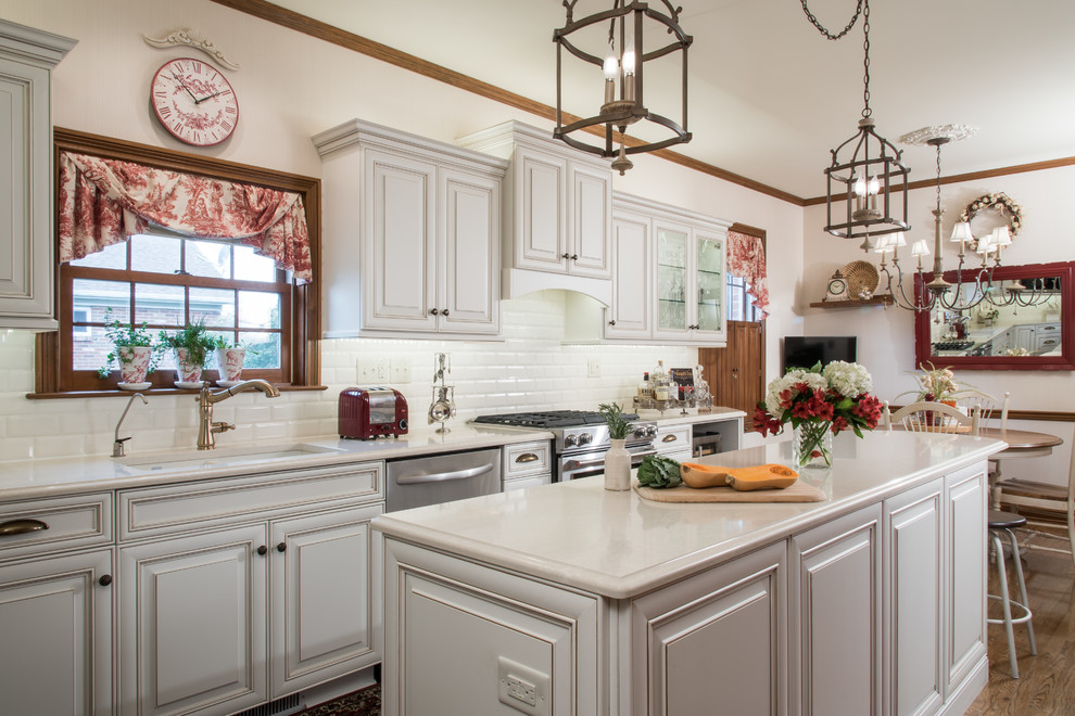 Mid-sized cottage galley medium tone wood floor and brown floor eat-in kitchen photo in St Louis with an undermount sink, raised-panel cabinets, white cabinets, quartz countertops, white backsplash, subway tile backsplash, stainless steel appliances and an island