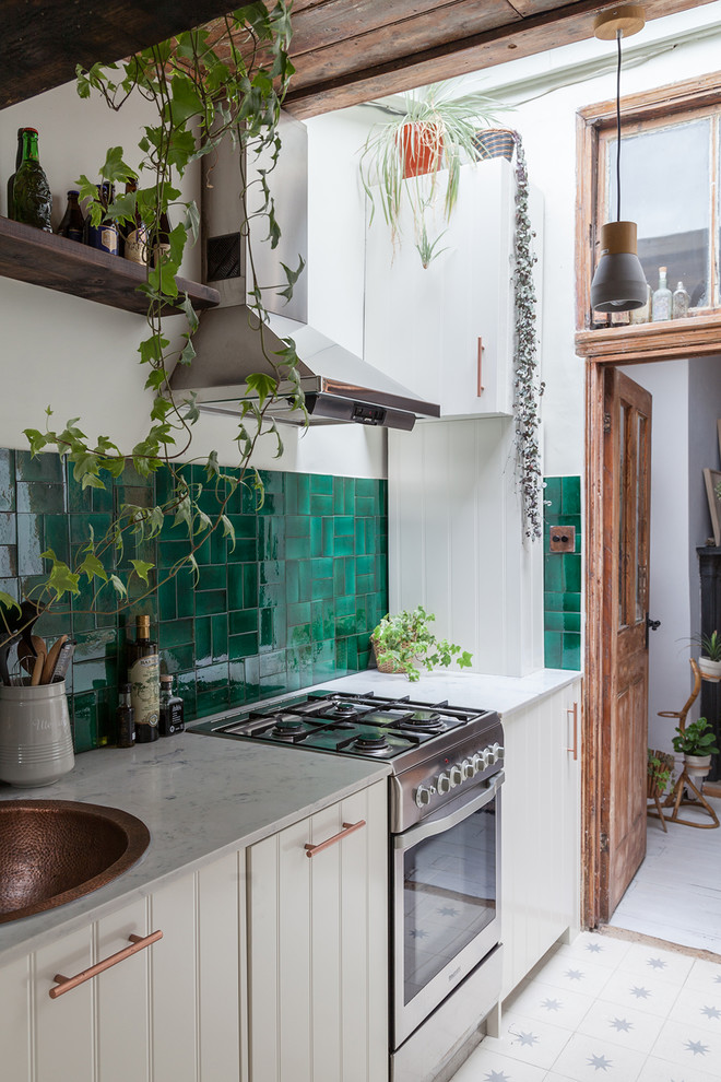 Foto på ett avskilt, litet eklektiskt l-kök, med en integrerad diskho, skåp i shakerstil, vita skåp, marmorbänkskiva, grönt stänkskydd, stänkskydd i keramik, integrerade vitvaror, cementgolv och vitt golv
