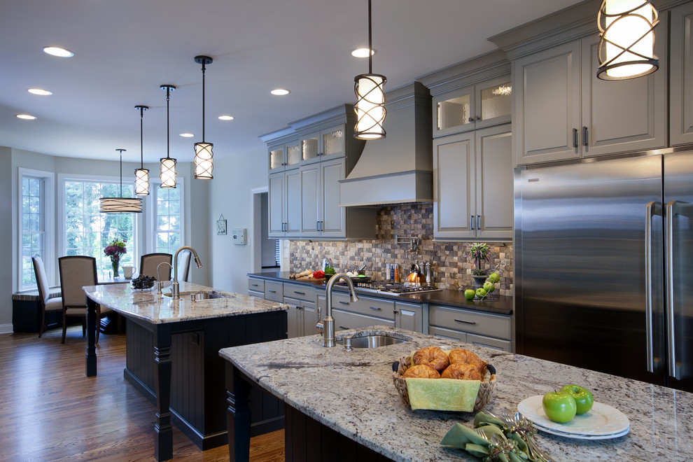 Example of a large transitional galley medium tone wood floor eat-in kitchen design in Other with an undermount sink, raised-panel cabinets, gray cabinets, granite countertops, multicolored backsplash, stone tile backsplash, stainless steel appliances and two islands