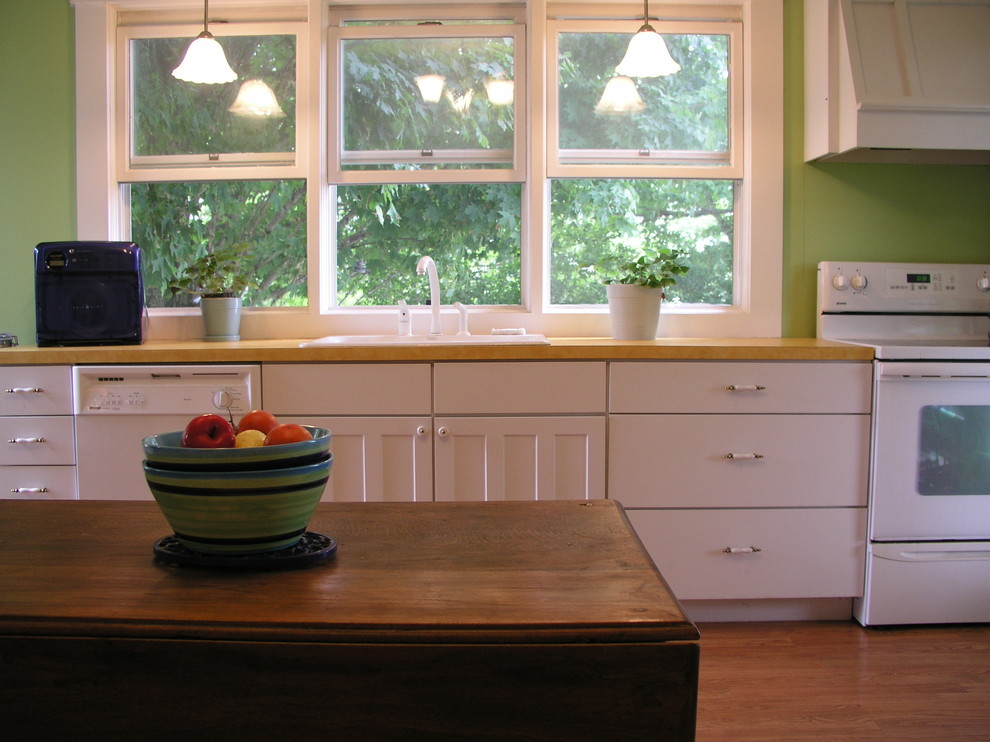 Modelo de cocina campestre con fregadero de doble seno, armarios estilo shaker, puertas de armario blancas, encimera de laminado y electrodomésticos blancos