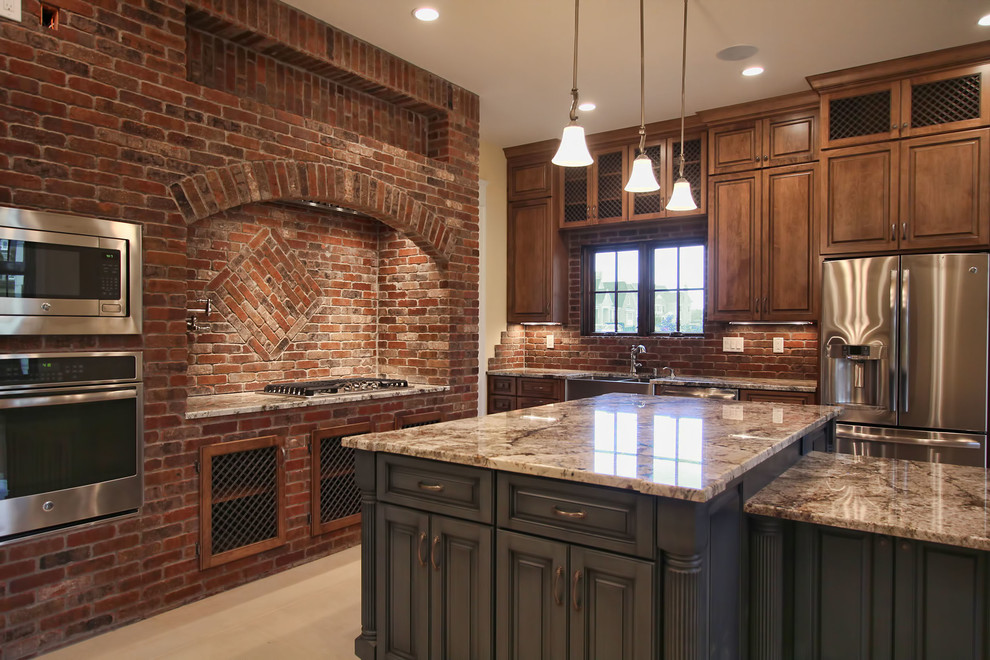 Example of a large classic l-shaped marble floor eat-in kitchen design in Louisville with a farmhouse sink, medium tone wood cabinets, granite countertops, brown backsplash, stone tile backsplash, stainless steel appliances and two islands