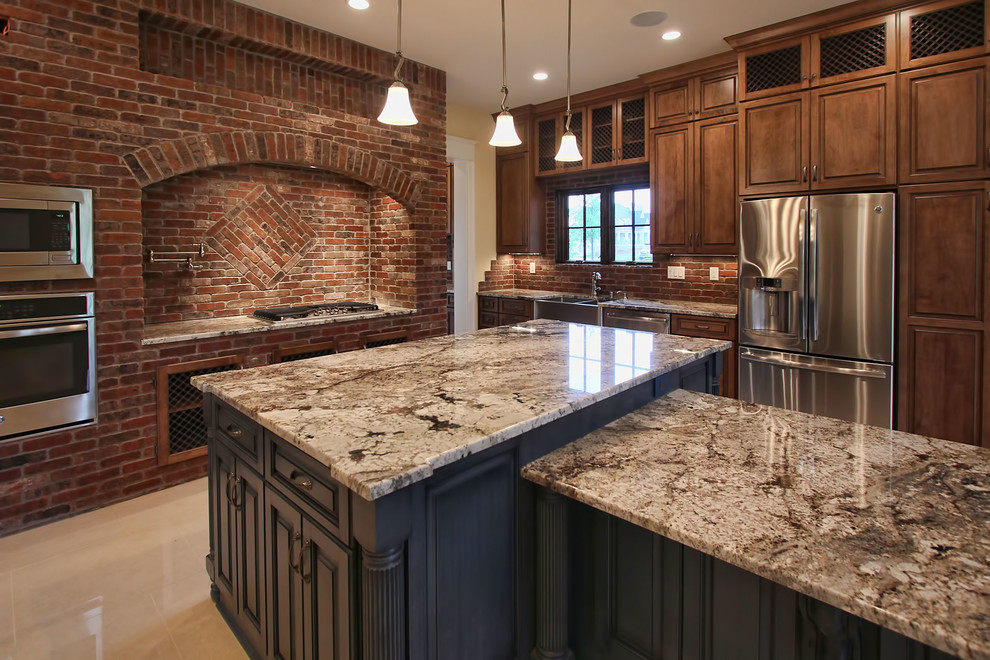 Inspiration for a large timeless l-shaped marble floor eat-in kitchen remodel in Louisville with a farmhouse sink, medium tone wood cabinets, granite countertops, brown backsplash, stone tile backsplash, stainless steel appliances and two islands