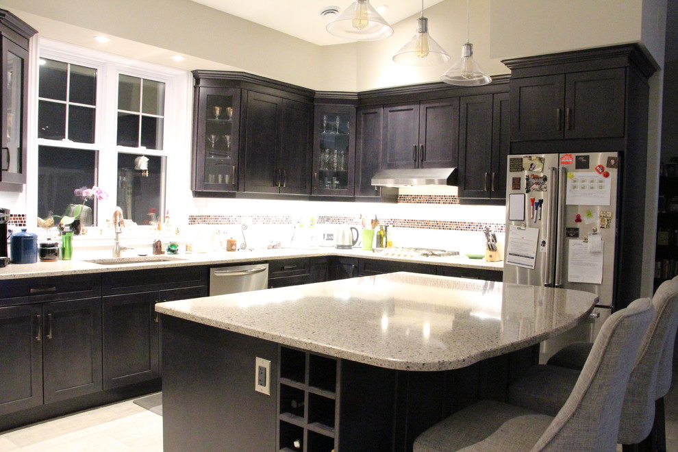This is an example of a medium sized traditional l-shaped kitchen/diner in Toronto with a submerged sink, shaker cabinets, grey cabinets, engineered stone countertops, white splashback, ceramic splashback, stainless steel appliances and an island.
