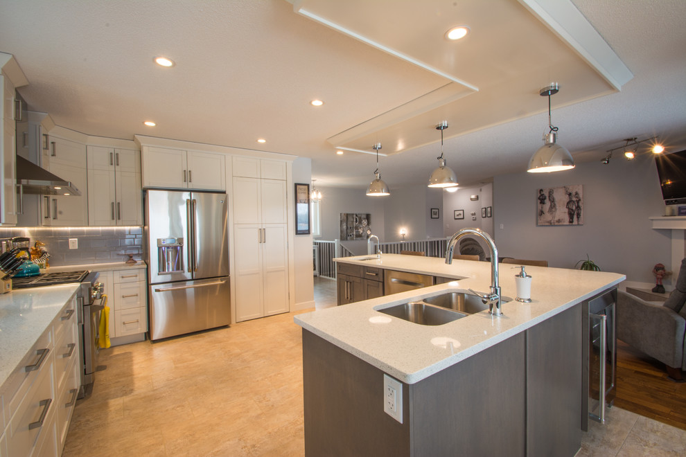 Inspiration for a mid-sized transitional l-shaped beige floor eat-in kitchen remodel with a double-bowl sink, shaker cabinets, white cabinets, gray backsplash, subway tile backsplash, stainless steel appliances and an island