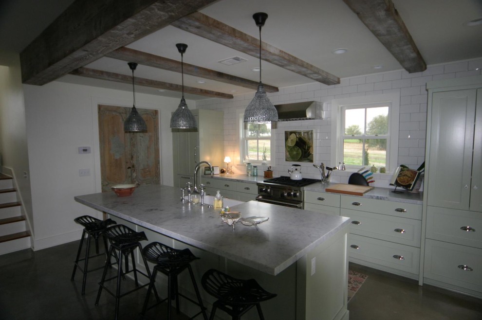 This is an example of a medium sized rural single-wall kitchen/diner in Austin with a belfast sink, shaker cabinets, white cabinets, composite countertops, white splashback, metro tiled splashback, stainless steel appliances, concrete flooring, an island and grey floors.