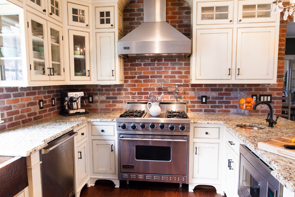 Exempel på ett mycket stort lantligt kök, med en rustik diskho, vita skåp, granitbänkskiva, rött stänkskydd, rostfria vitvaror, mellanmörkt trägolv, skåp i shakerstil och stänkskydd i tegel