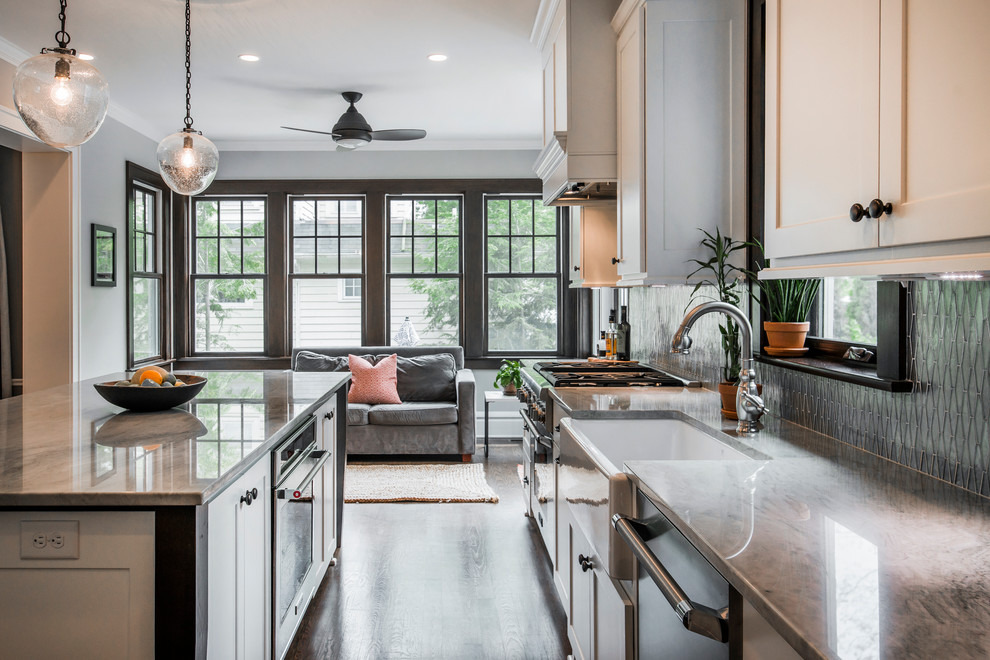 Large transitional l-shaped medium tone wood floor eat-in kitchen photo in Columbus with a farmhouse sink, shaker cabinets, white cabinets, quartzite countertops, metallic backsplash, glass tile backsplash, stainless steel appliances and an island