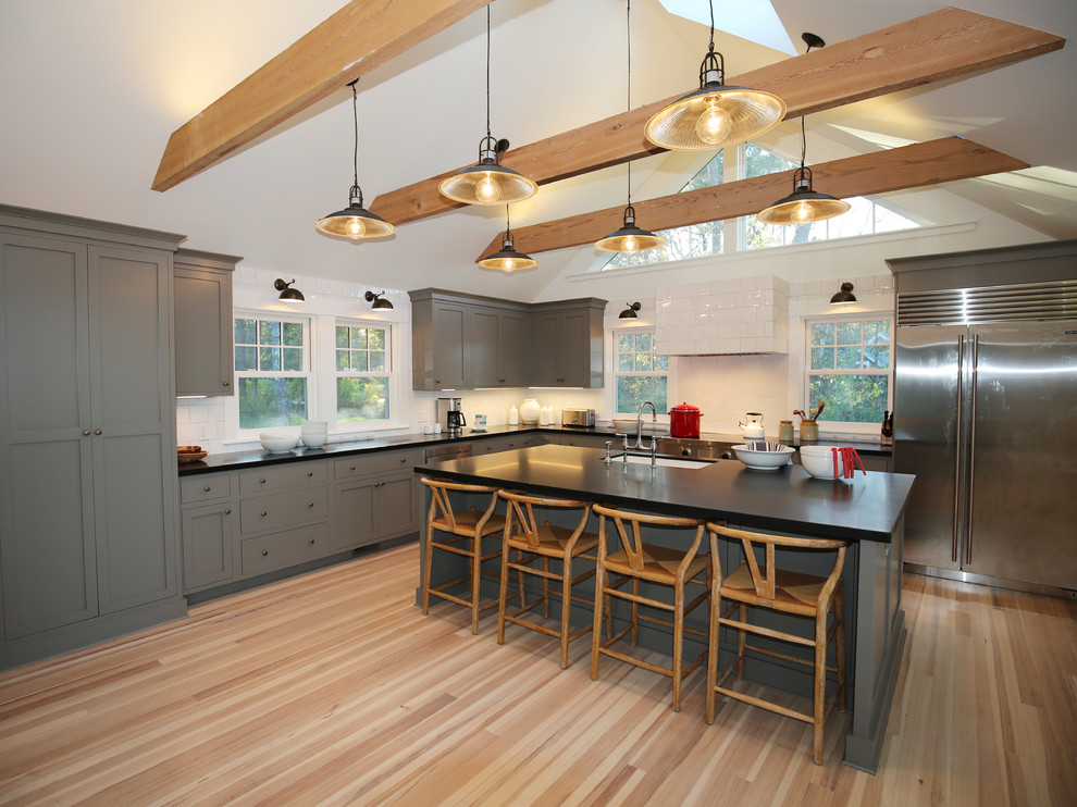 Exempel på ett lantligt l-kök, med en undermonterad diskho, skåp i shakerstil, grå skåp, gult stänkskydd, stänkskydd i tunnelbanekakel, rostfria vitvaror, ljust trägolv och en köksö