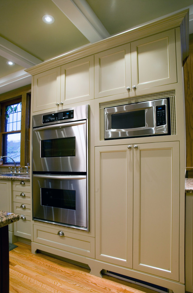 Bild på ett stort funkis kök, med en dubbel diskho, luckor med profilerade fronter, vita skåp, rostfria vitvaror, ljust trägolv, en köksö, granitbänkskiva, beige stänkskydd och stänkskydd i keramik