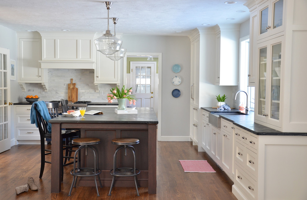 Klassische Küche mit Landhausspüle, Schrankfronten mit vertiefter Füllung, Speckstein-Arbeitsplatte, Rückwand aus Steinfliesen, braunem Holzboden und Kücheninsel in Boston