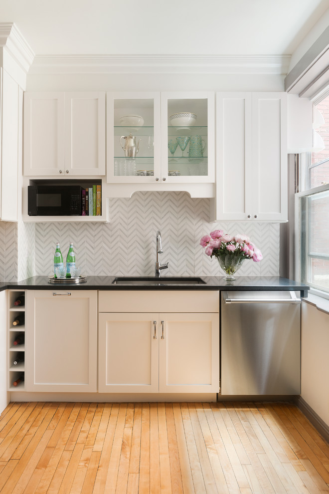 Exempel på ett klassiskt kök, med en undermonterad diskho, skåp i shakerstil, vita skåp, vitt stänkskydd, rostfria vitvaror, mellanmörkt trägolv och granitbänkskiva