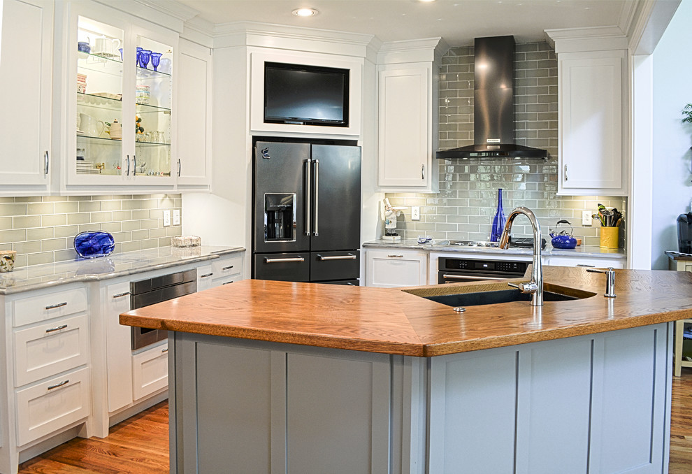 Mid-sized transitional l-shaped medium tone wood floor open concept kitchen photo in Charlotte with an undermount sink, shaker cabinets, white cabinets, wood countertops, gray backsplash, glass tile backsplash, stainless steel appliances and an island