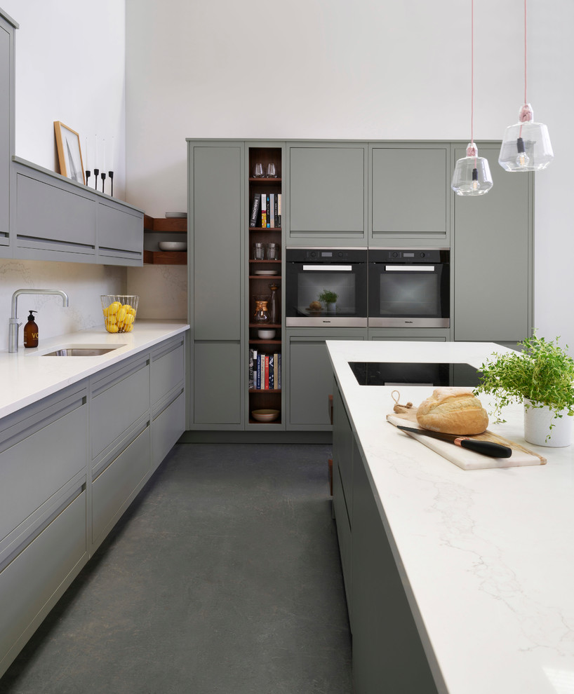 Modern inredning av ett mellanstort kök, med släta luckor, grå skåp, bänkskiva i kvartsit, vitt stänkskydd, stänkskydd i marmor, betonggolv, en halv köksö och grått golv
