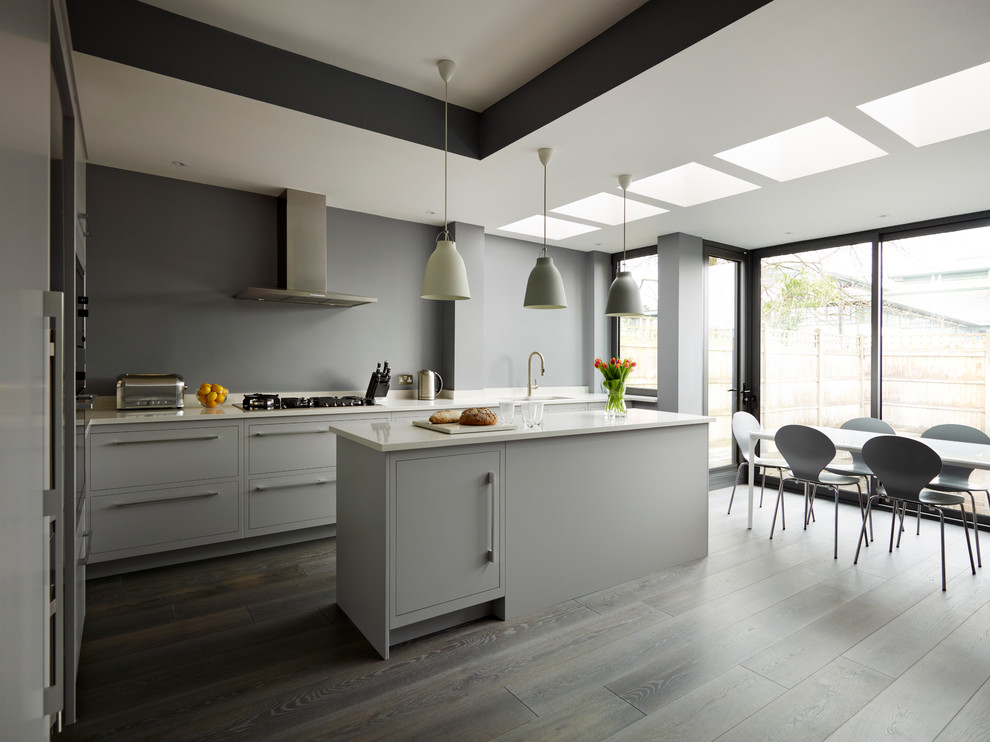 Cette image montre une cuisine design avec un placard à porte plane, des portes de placard grises, une crédence grise, îlot et un sol gris.