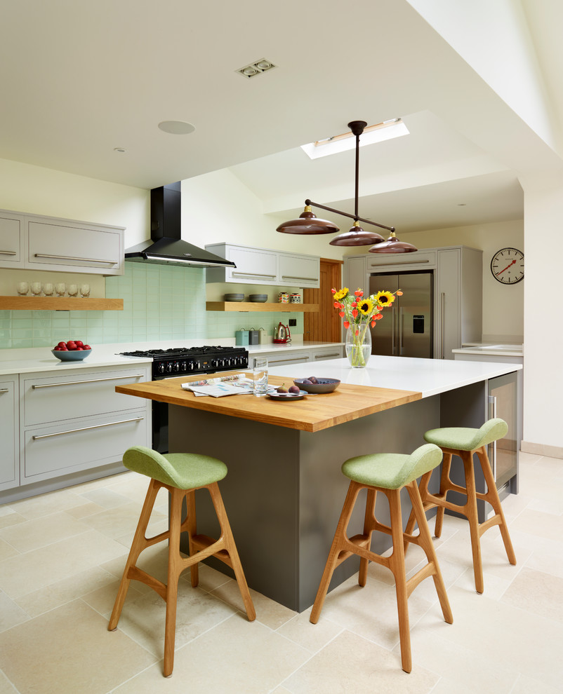ロンドンにあるエクレクティックスタイルのおしゃれなアイランドキッチン (フラットパネル扉のキャビネット、緑のキッチンパネル、サブウェイタイルのキッチンパネル、シルバーの調理設備) の写真