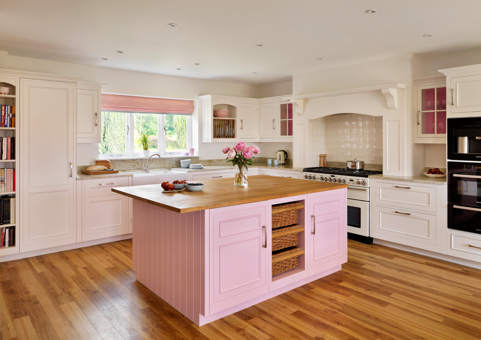 Example of a farmhouse l-shaped kitchen design in London with white appliances and an island