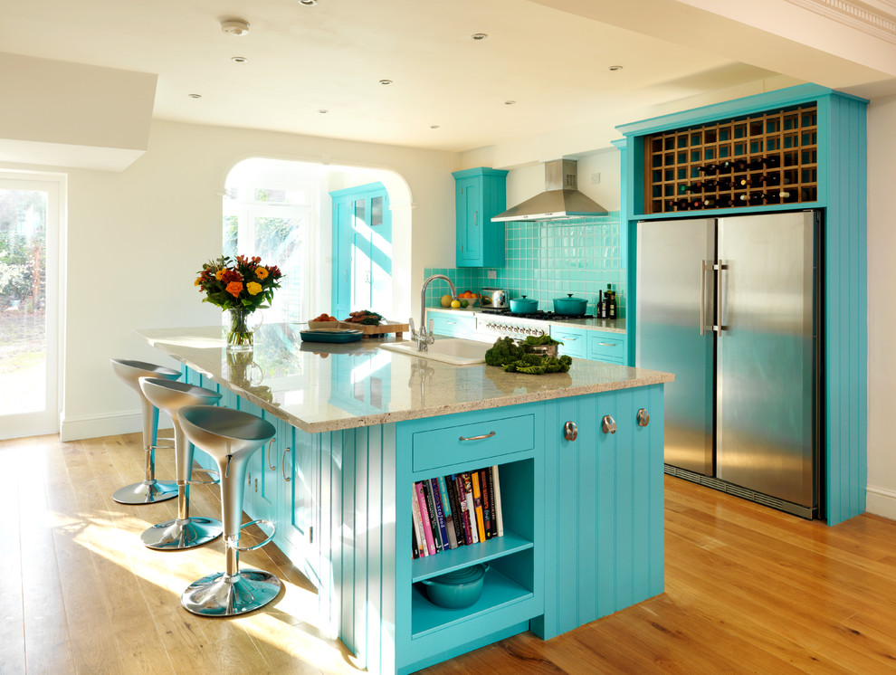 Zweizeilige Klassische Küchenbar mit Einbauwaschbecken, blauen Schränken, Küchenrückwand in Blau, Küchengeräten aus Edelstahl, braunem Holzboden und Kücheninsel in London