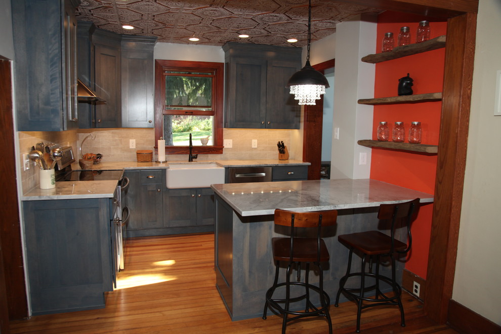 Bild på ett litet lantligt kök, med en rustik diskho, släta luckor, blå skåp, granitbänkskiva, beige stänkskydd, stänkskydd i keramik, rostfria vitvaror, ljust trägolv och en halv köksö