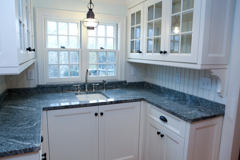 Mittelgroße Klassische Wohnküche mit Landhausspüle, Glasfronten, weißen Schränken, Marmor-Arbeitsplatte, Küchenrückwand in Weiß und braunem Holzboden in Boston