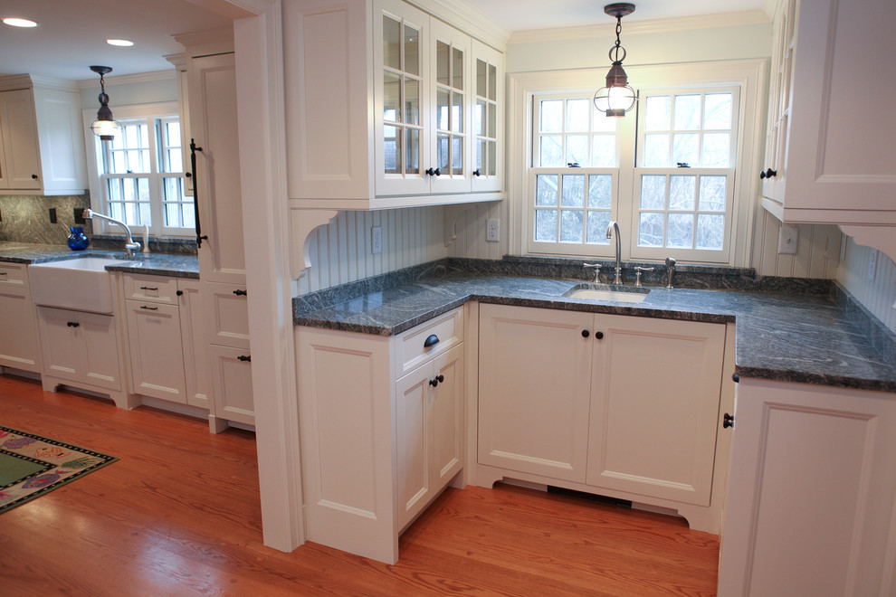 Eat-in kitchen - mid-sized traditional medium tone wood floor eat-in kitchen idea in Boston with a farmhouse sink, glass-front cabinets, white cabinets, marble countertops and white backsplash