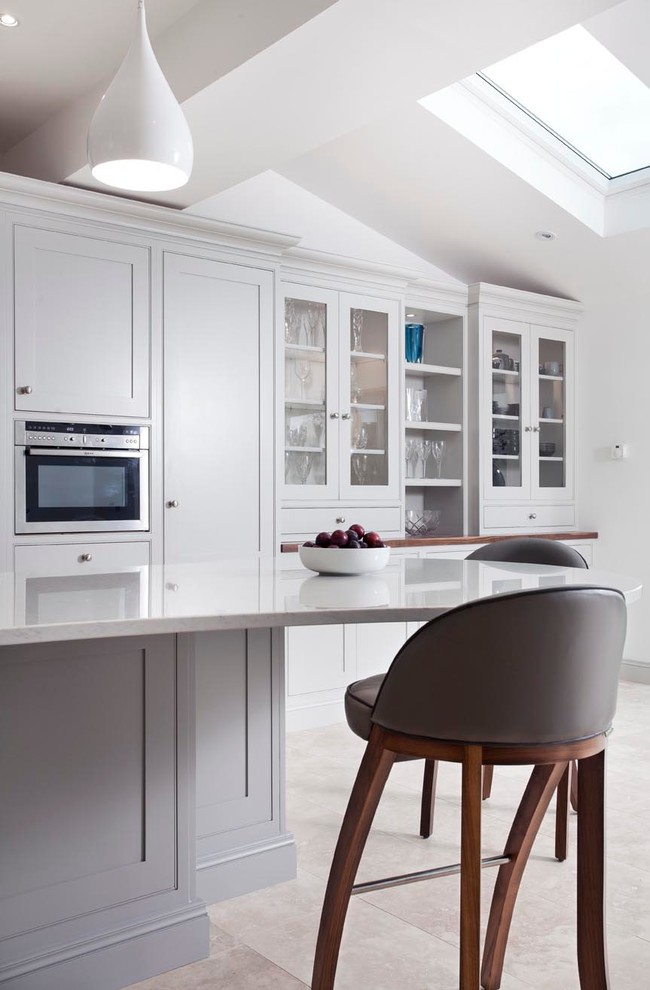 Modern inredning av ett kök, med en undermonterad diskho, skåp i shakerstil, grå skåp, bänkskiva i kvarts, stänkskydd i sten, marmorgolv och en köksö