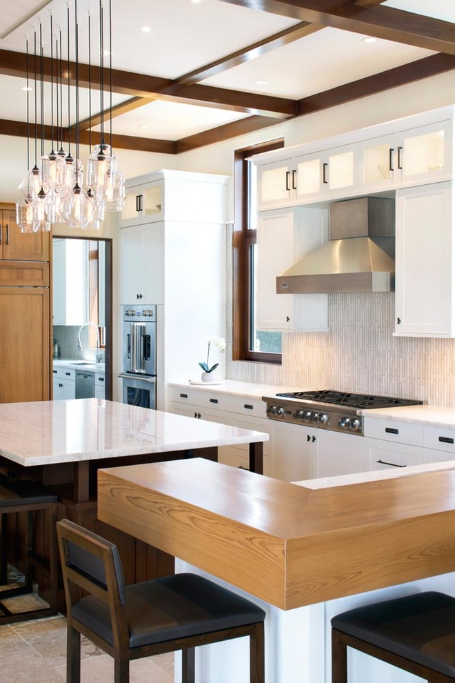 Inspiration for a transitional kitchen remodel in Miami with recessed-panel cabinets, white cabinets, beige backsplash and stainless steel appliances