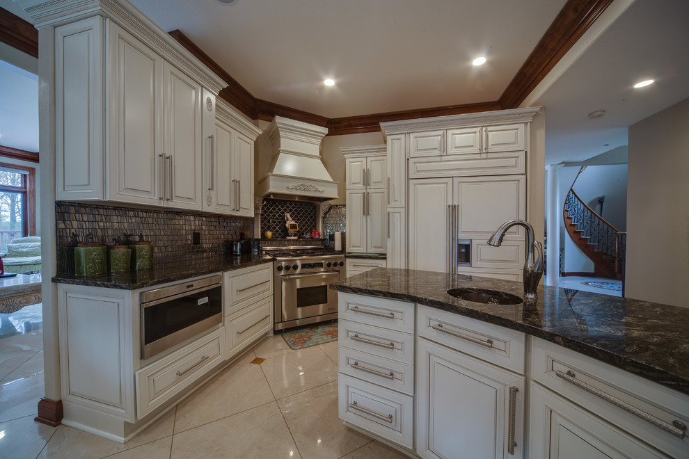 Expansive mediterranean u-shaped kitchen/diner in Milwaukee with a submerged sink, raised-panel cabinets, white cabinets, granite worktops, mosaic tiled splashback, stainless steel appliances, marble flooring, an island and white floors.