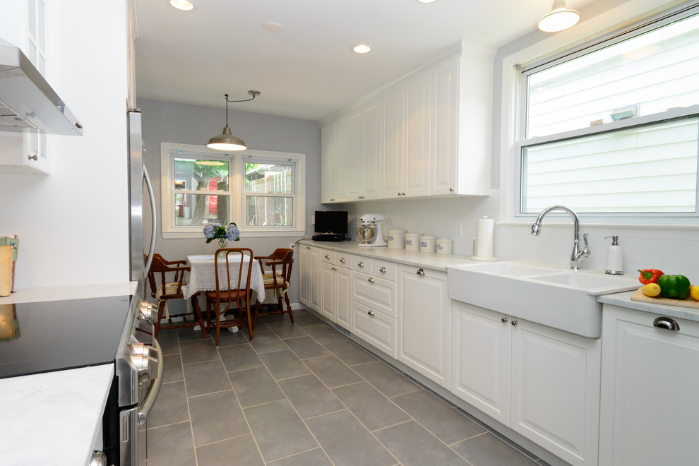 Mid-sized transitional galley ceramic tile enclosed kitchen photo in New York with a farmhouse sink, white cabinets, marble countertops, white backsplash, subway tile backsplash, stainless steel appliances and no island