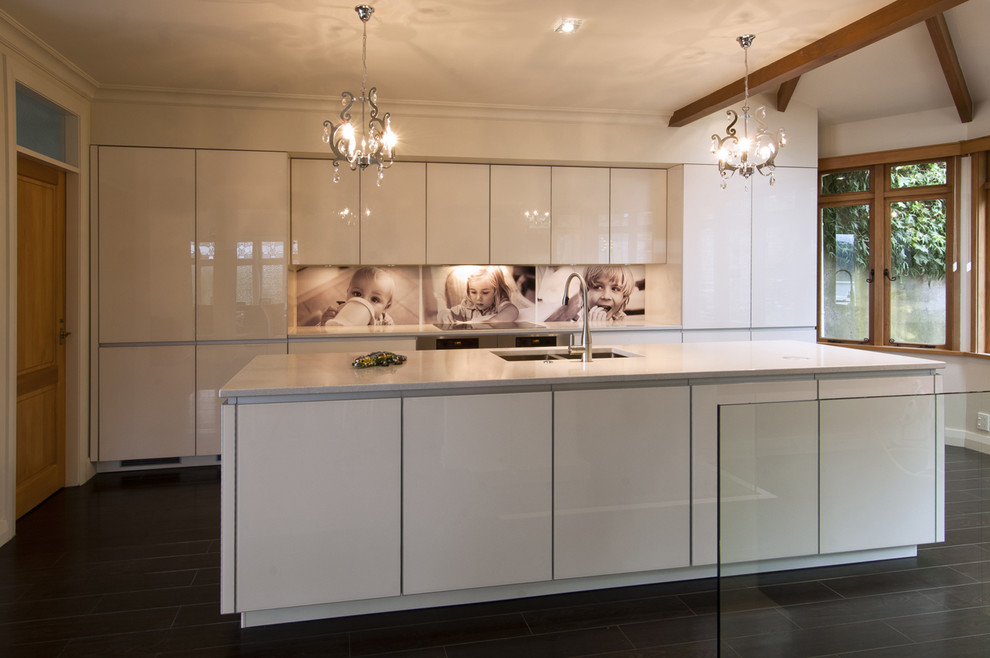 Zweizeilige Moderne Küche mit Unterbauwaschbecken, weißen Schränken, Quarzwerkstein-Arbeitsplatte, bunter Rückwand, Glasrückwand, bunten Elektrogeräten, dunklem Holzboden und Kücheninsel in Wellington