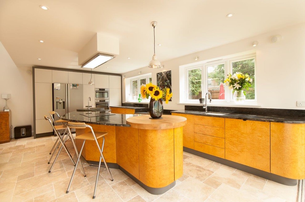 Inspiration for a large contemporary galley kitchen/diner in Other with a built-in sink, flat-panel cabinets, light wood cabinets, granite worktops, black splashback, ceramic splashback, stainless steel appliances, slate flooring, an island and beige floors.
