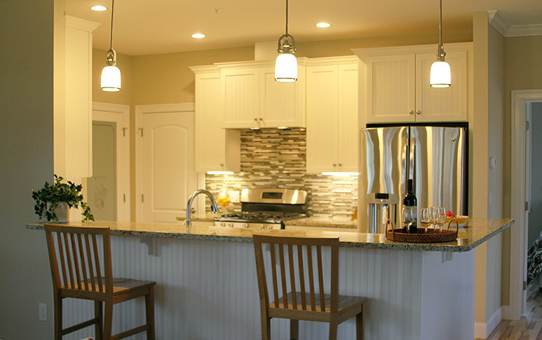 Idéer för att renovera ett mellanstort lantligt kök, med en undermonterad diskho, luckor med infälld panel, vita skåp, granitbänkskiva, flerfärgad stänkskydd, stänkskydd i porslinskakel, rostfria vitvaror, mellanmörkt trägolv och en halv köksö