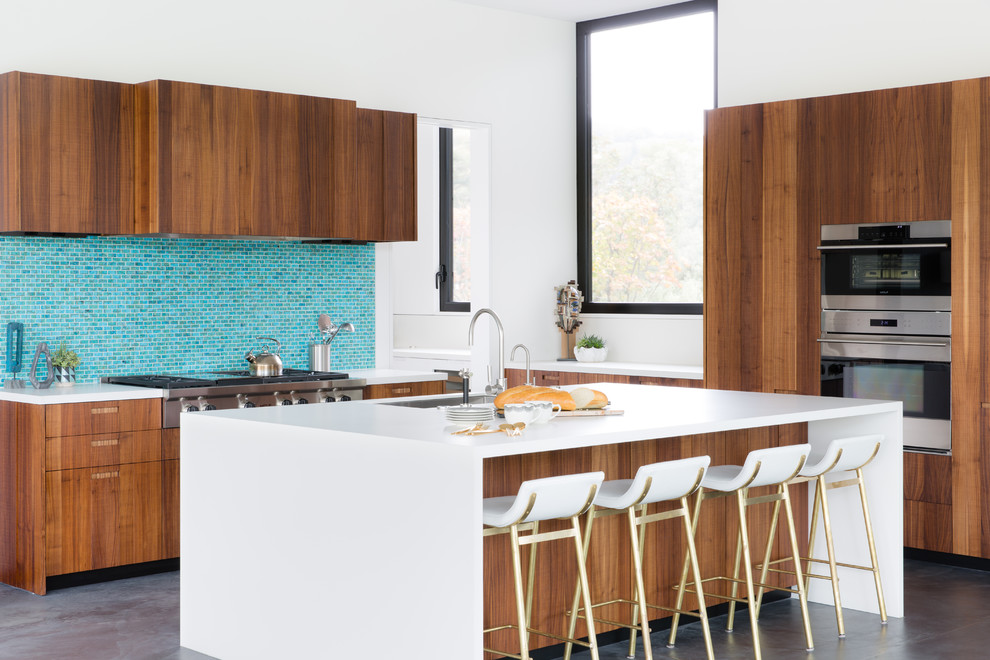 Idée de décoration pour une cuisine ouverte encastrable design en L et bois brun avec un évier encastré, un placard à porte plane, une crédence bleue, une crédence en mosaïque, sol en béton ciré, îlot et un sol gris.