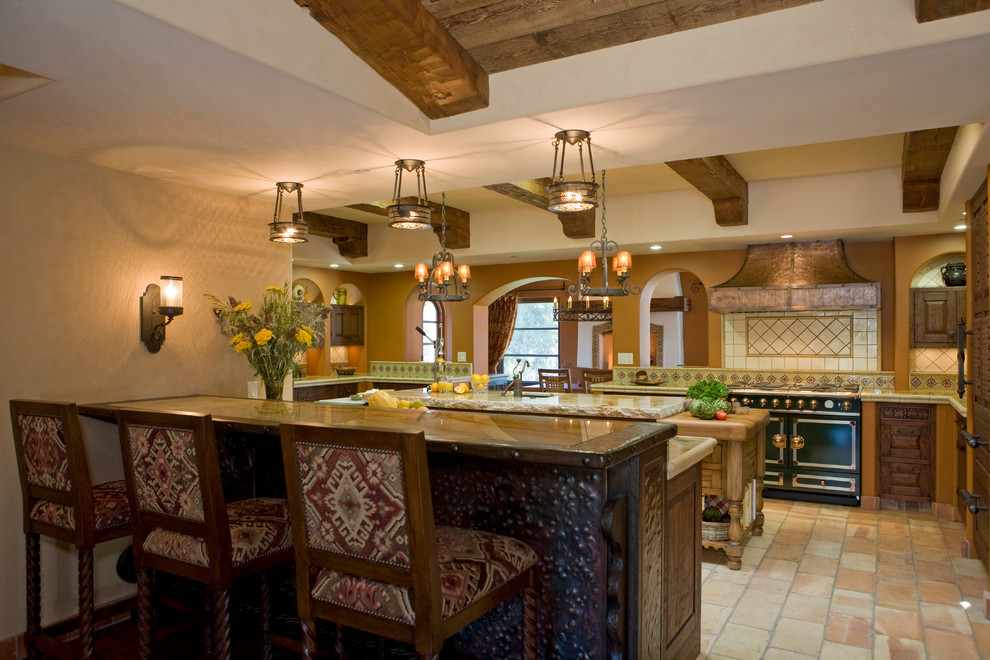 Foto di una cucina ad U mediterranea con ante con bugna sagomata, ante in legno bruno, paraspruzzi beige e elettrodomestici neri
