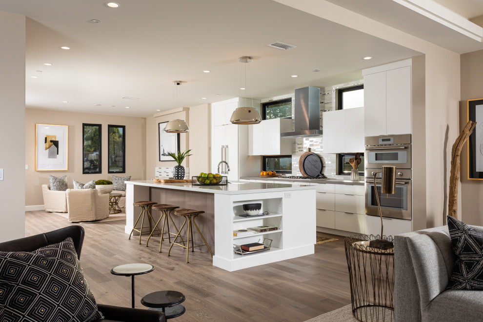 Open concept kitchen - contemporary galley dark wood floor and brown floor open concept kitchen idea in Orange County with an undermount sink, flat-panel cabinets, white cabinets, stainless steel appliances, an island and gray countertops