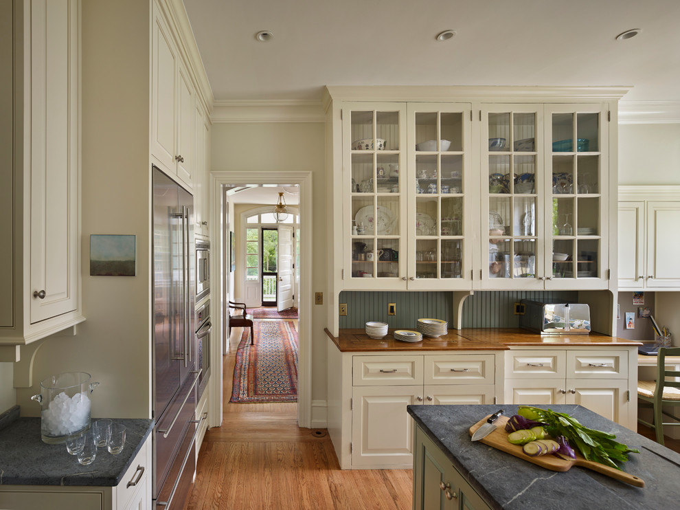 Inspiration for a timeless kitchen remodel in Philadelphia with soapstone countertops, glass-front cabinets, beige cabinets and stainless steel appliances
