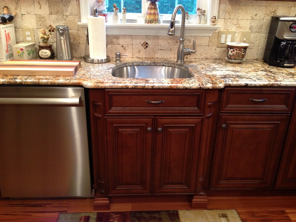 Bild på ett medelhavsstil kök, med en undermonterad diskho, luckor med upphöjd panel, skåp i mörkt trä, granitbänkskiva, beige stänkskydd, stänkskydd i stenkakel och rostfria vitvaror