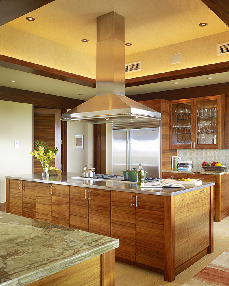 ハワイにあるトロピカルスタイルのおしゃれなキッチン (フラットパネル扉のキャビネット、シルバーの調理設備) の写真