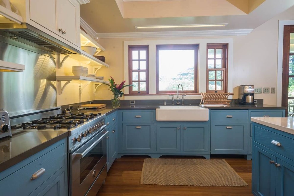 Klassisk inredning av ett avskilt, stort l-kök, med en rustik diskho, luckor med profilerade fronter, blå skåp, bänkskiva i kvarts, integrerade vitvaror, mellanmörkt trägolv, en köksö och brunt golv