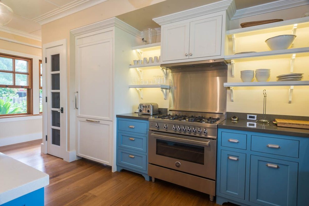 Inspiration for a large traditional l-shaped enclosed kitchen in Hawaii with a belfast sink, beaded cabinets, blue cabinets, engineered stone countertops, integrated appliances, medium hardwood flooring, an island and brown floors.
