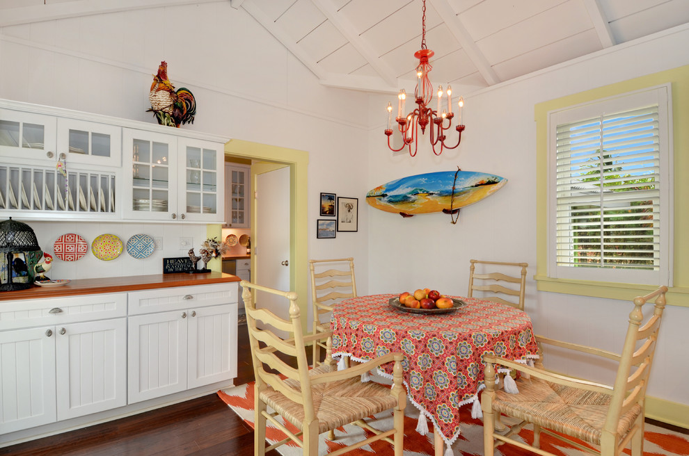 Foto de cocina comedor tropical sin isla con suelo de madera oscura, armarios con rebordes decorativos y puertas de armario blancas