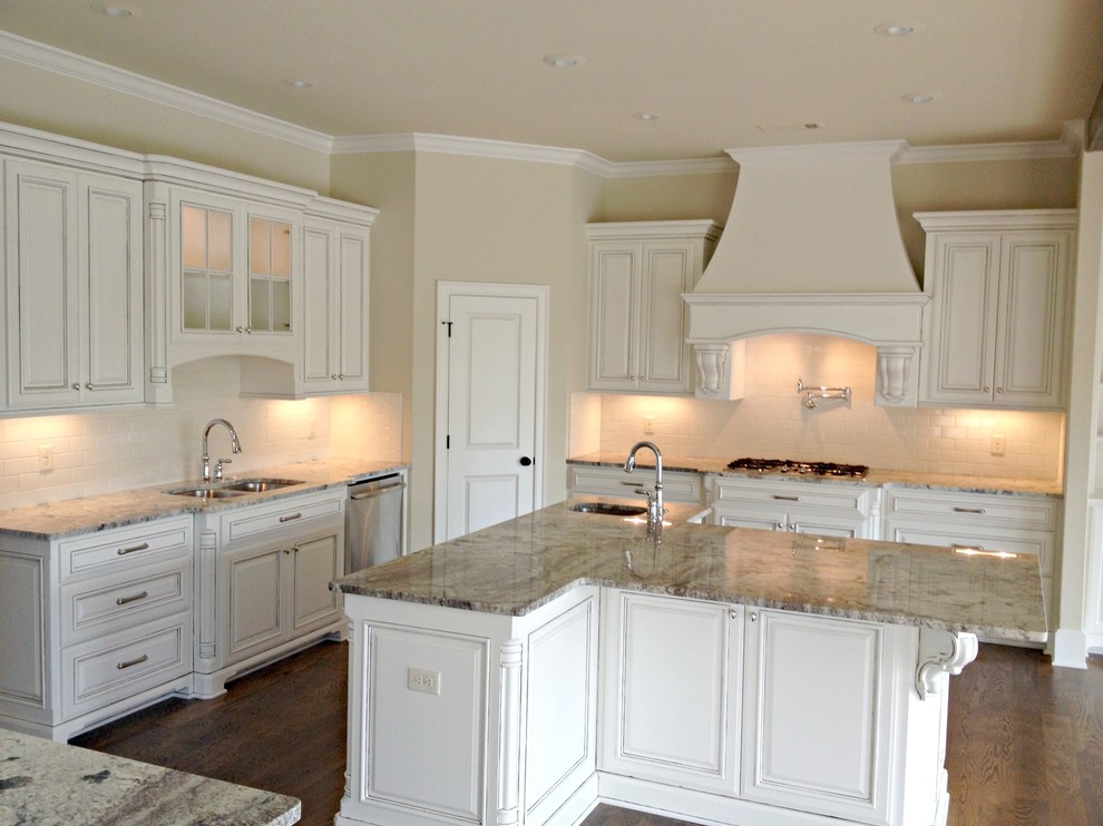 Large elegant u-shaped medium tone wood floor eat-in kitchen photo in Little Rock with a double-bowl sink, raised-panel cabinets, white cabinets, granite countertops, white backsplash, subway tile backsplash, stainless steel appliances and an island