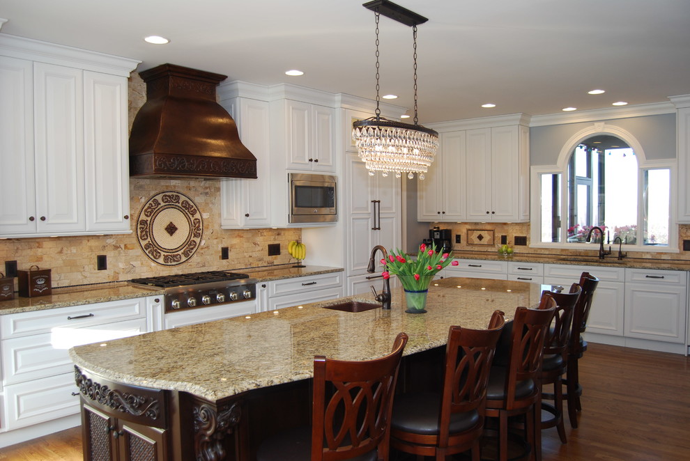 Inspiration for a large timeless l-shaped medium tone wood floor eat-in kitchen remodel in Cincinnati with an undermount sink, raised-panel cabinets, white cabinets, granite countertops, beige backsplash, stone tile backsplash, paneled appliances and an island