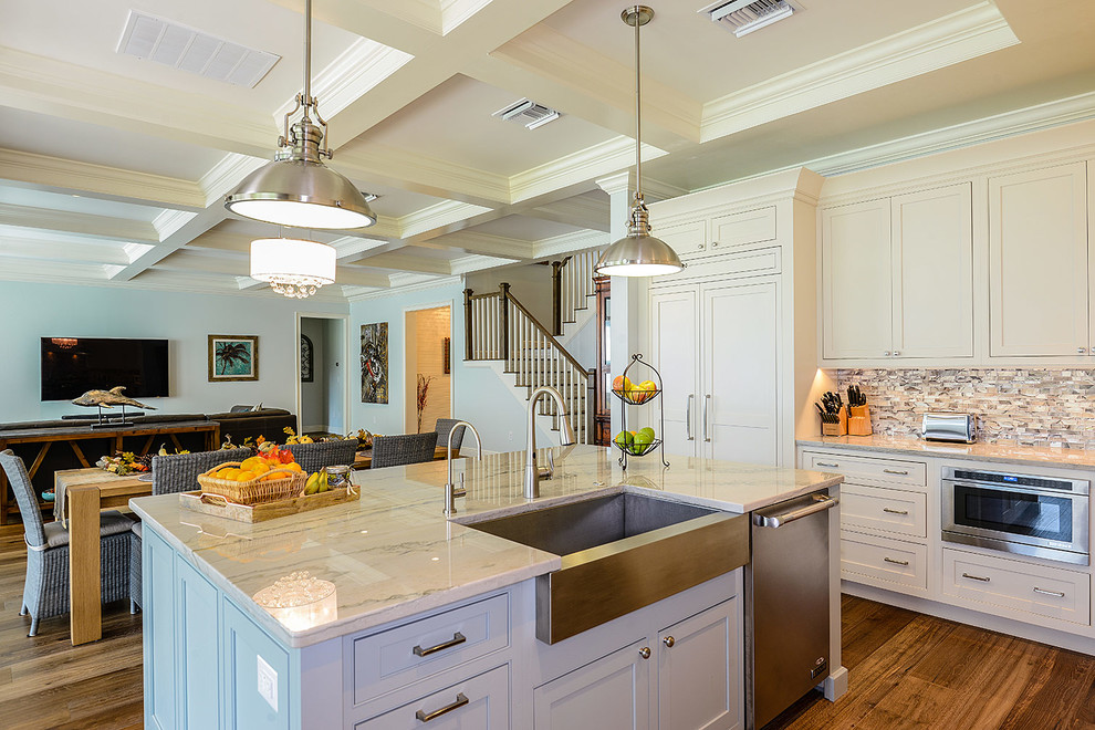Large transitional l-shaped light wood floor open concept kitchen photo in Tampa with a farmhouse sink, beaded inset cabinets, white cabinets, quartzite countertops, metallic backsplash, glass tile backsplash, stainless steel appliances and an island
