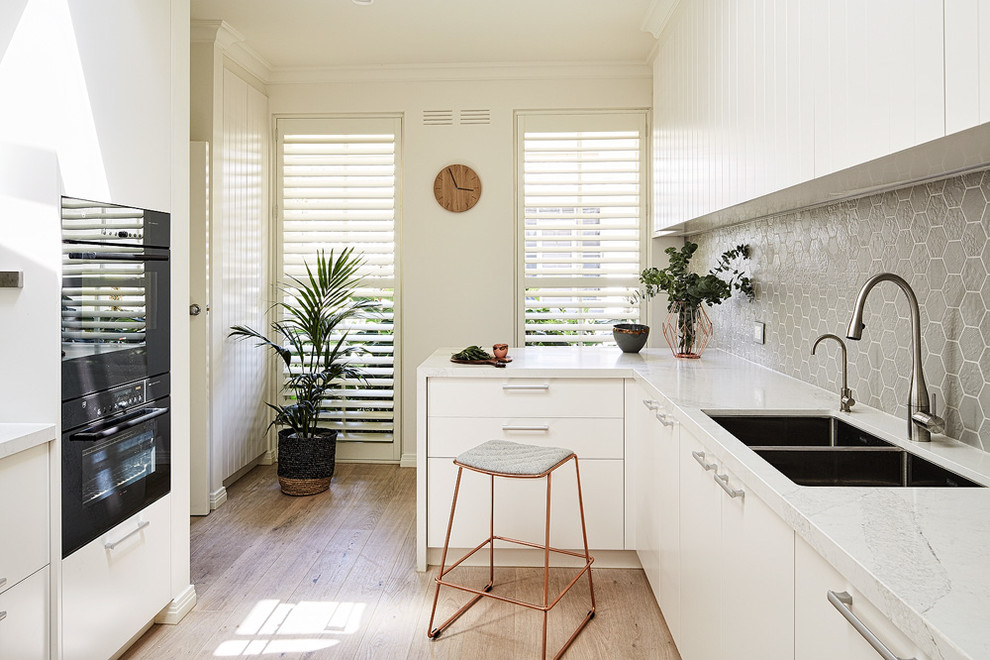 Foto di una piccola cucina design chiusa con ante bianche, top in superficie solida, paraspruzzi grigio, paraspruzzi con piastrelle in ceramica e parquet chiaro