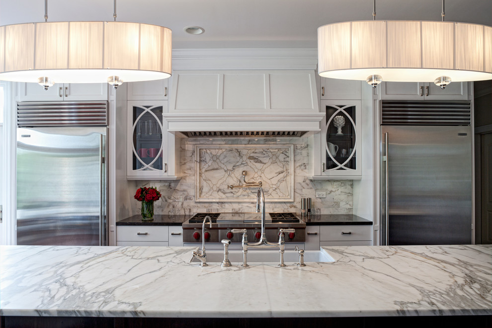 Cette image montre une cuisine traditionnelle avec des portes de placard blanches, plan de travail en marbre et un électroménager en acier inoxydable.
