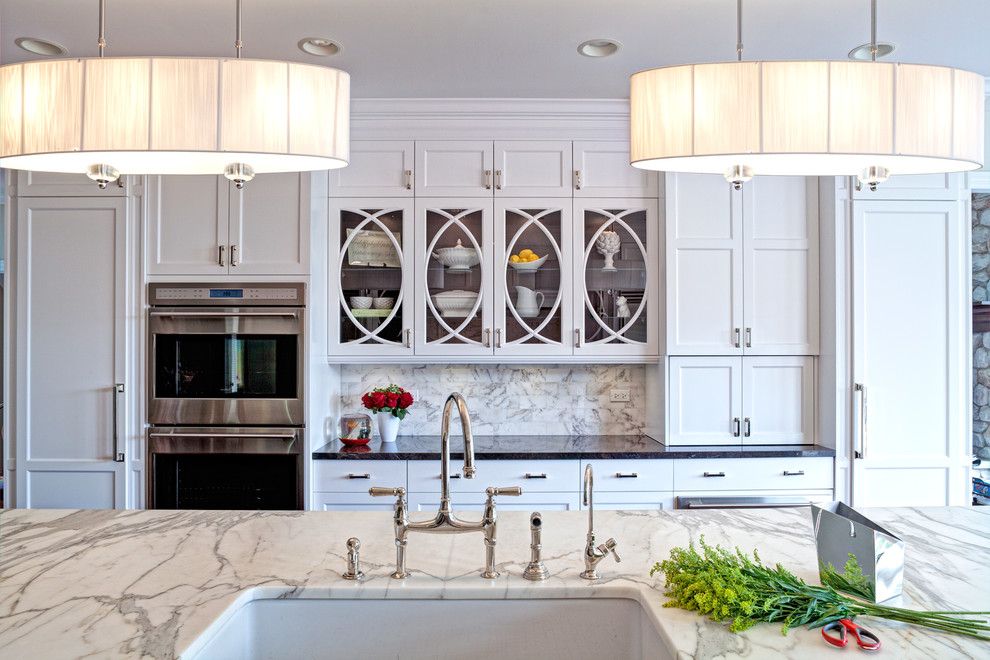 Imagen de cocina tradicional renovada con puertas de armario blancas, encimera de mármol y electrodomésticos de acero inoxidable