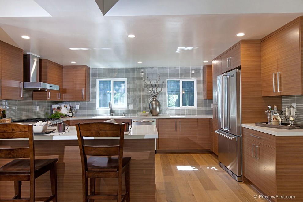 Klassische Küche in U-Form mit flächenbündigen Schrankfronten, hellbraunen Holzschränken, Quarzit-Arbeitsplatte, Küchengeräten aus Edelstahl, hellem Holzboden und Halbinsel in San Diego